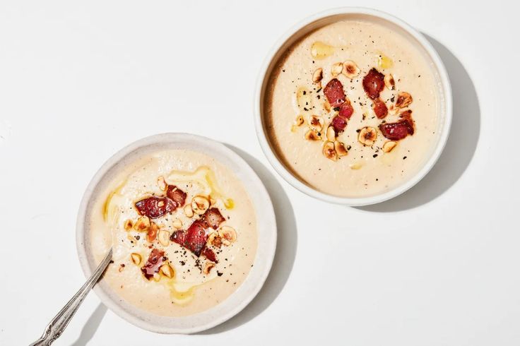 two bowls filled with food sitting on top of a white table next to each other