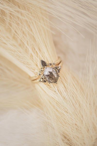 a diamond ring sitting on top of some white feathers with long hair in the foreground