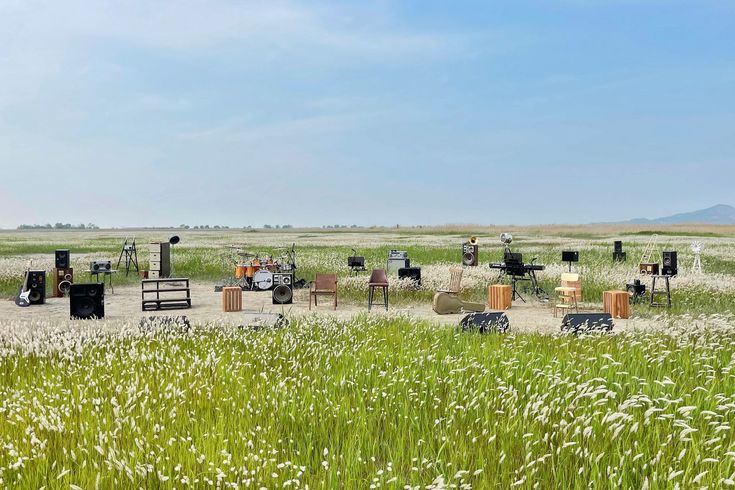 there are many chairs and tables in the middle of an open field with tall grass