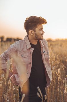 a man standing in a wheat field with his hands on his hips and looking off into the distance