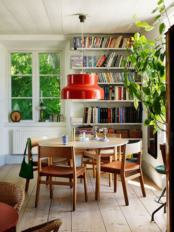 a dining room table and chairs in front of a bookshelf filled with books