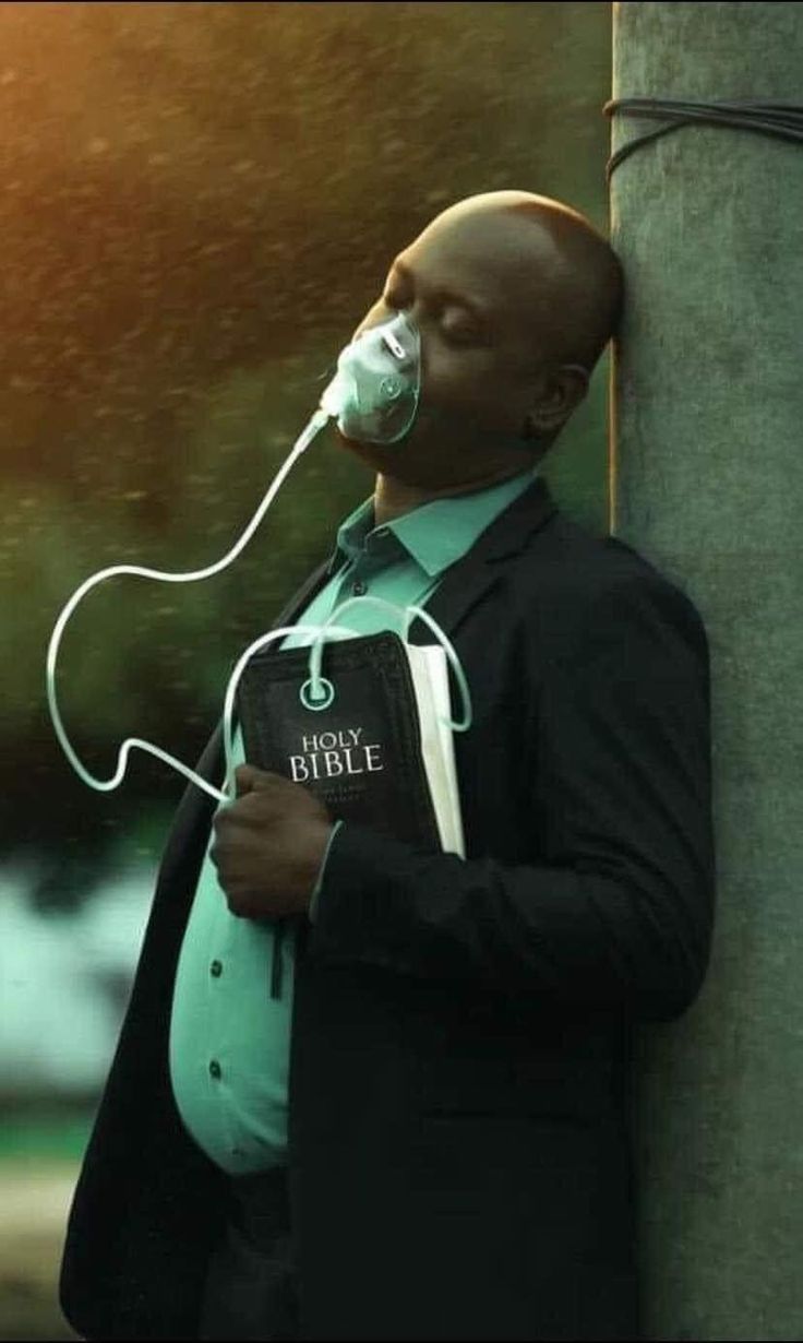 a man with an oxygen mask on leaning against a pole and listening to headphones