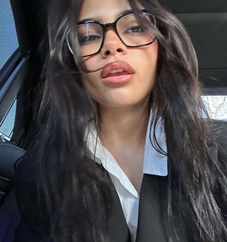 a woman wearing glasses sitting in the back seat of a car