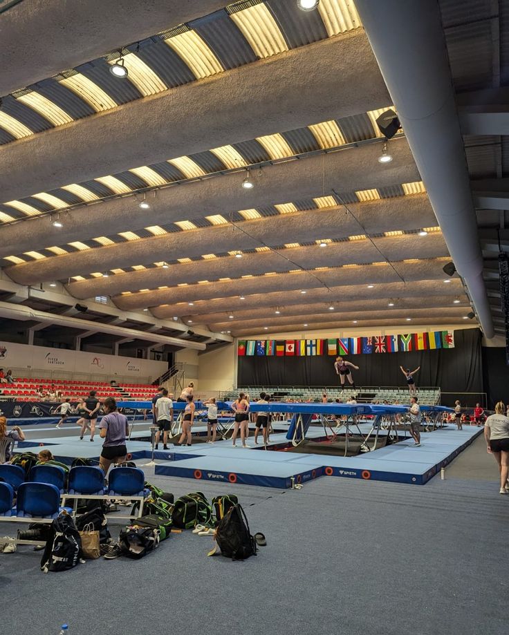 people are playing ping pong in an indoor arena with many tables and chairs on the floor