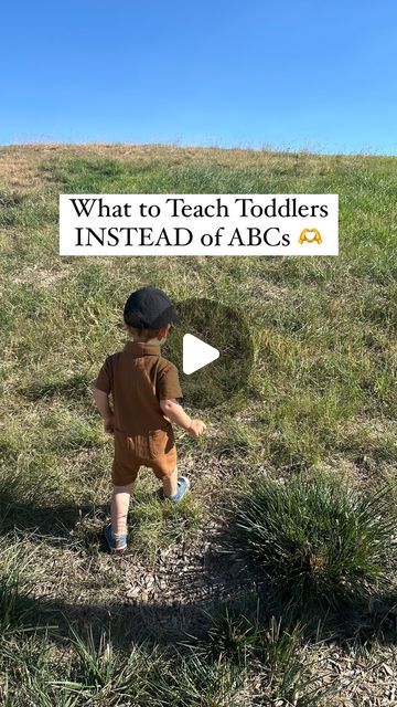 a little boy standing on top of a grass covered field with the words what to teach toddlers instead of abc's