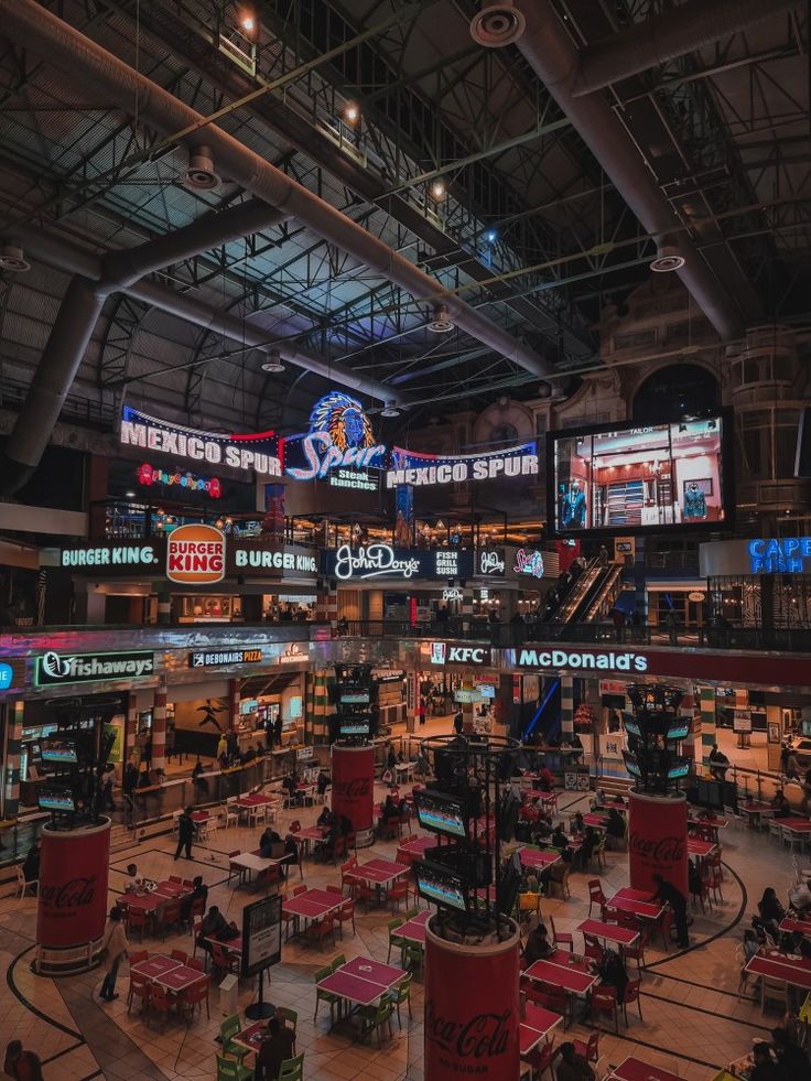 the inside of a sports arena with tables, chairs and televisions on the walls