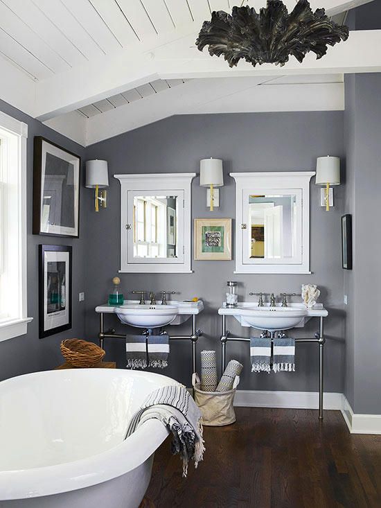 a bathroom with two sinks and a bathtub in it's center, surrounded by framed pictures on the wall