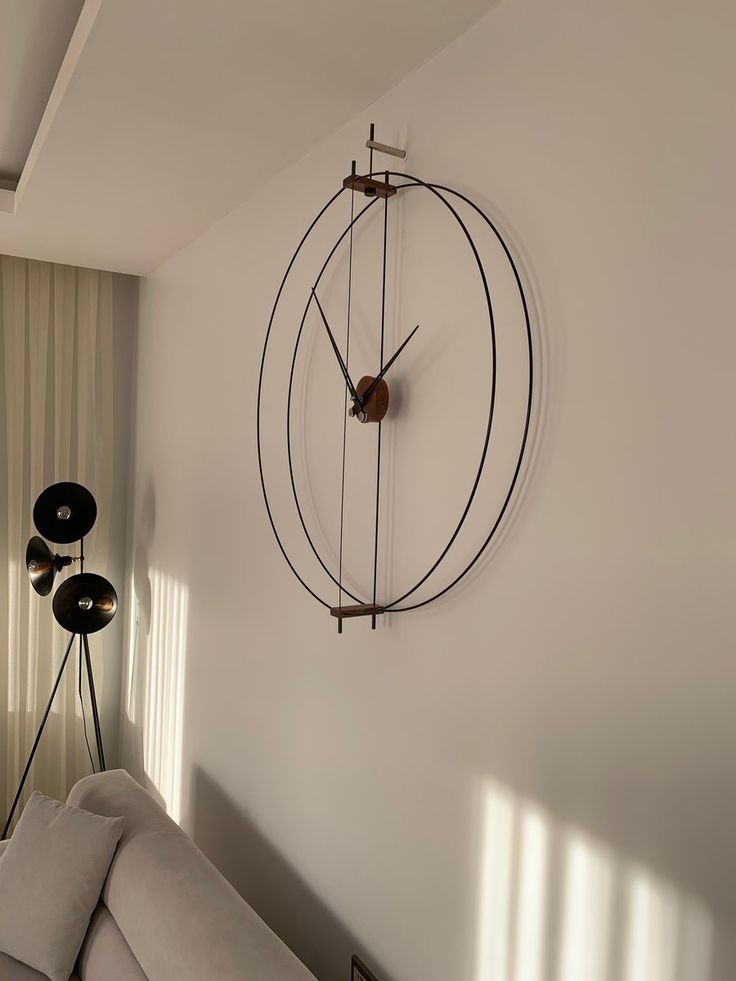 a living room with a large clock mounted to the wall next to a couch in front of a window