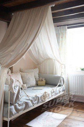 a white canopy bed sitting in a bedroom next to a window