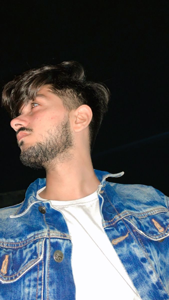 a man wearing a denim jacket looking off into the distance