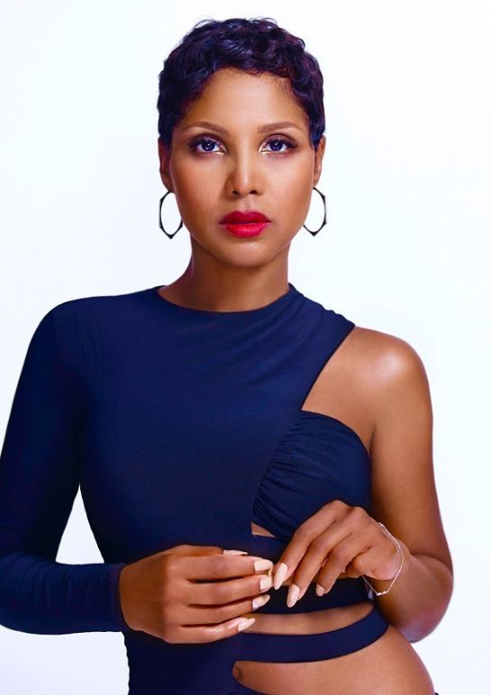 a woman in a blue dress with her hands on her hip and wearing large hoop earrings