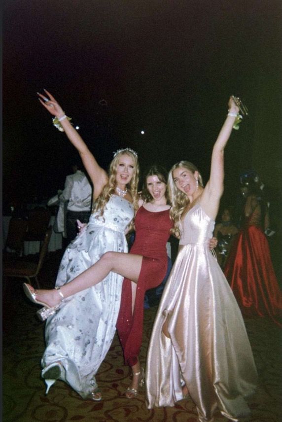 three women in dresses are posing for the camera with their arms up and legs spread out