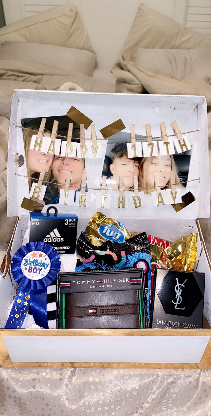 a birthday gift box with two pictures and ribbons in it on a bed next to a pillow