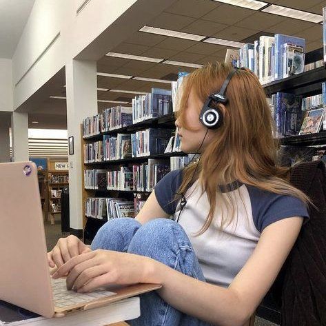 a woman sitting in front of a laptop wearing headphones