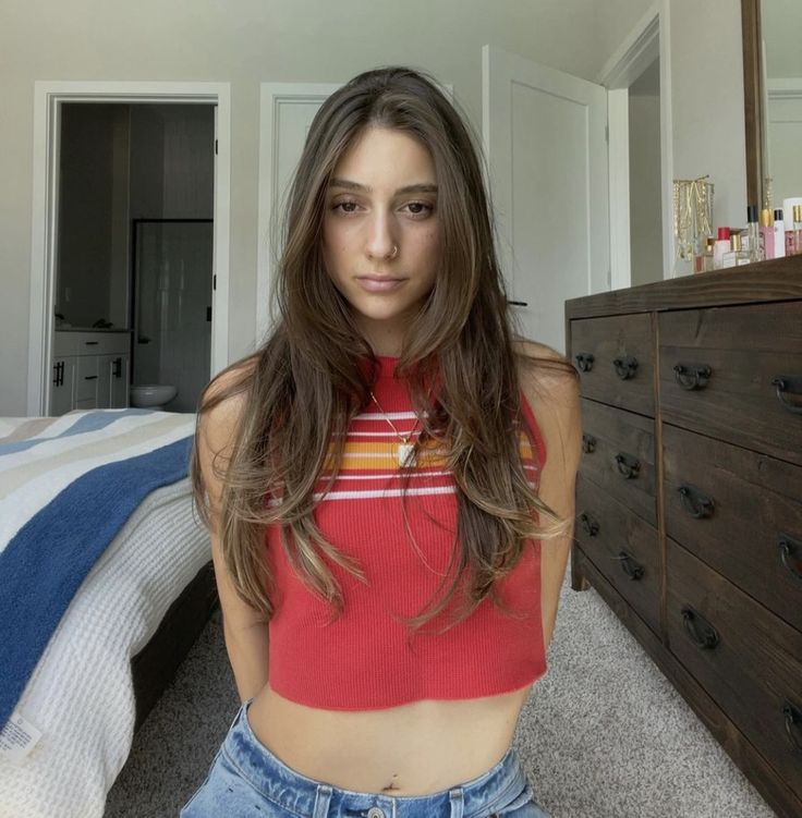 a young woman is posing for the camera in front of a bed with drawers and dressers