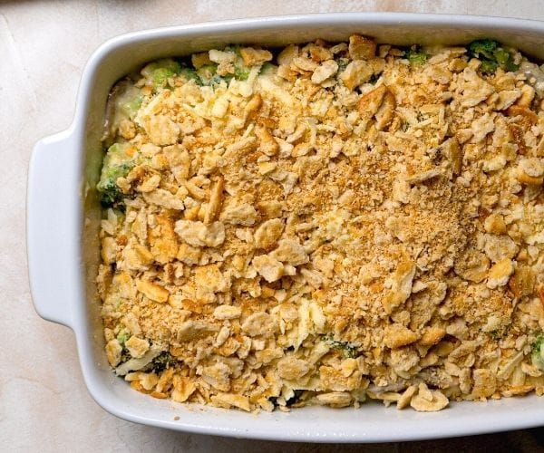 a casserole dish filled with broccoli and other toppings on a table