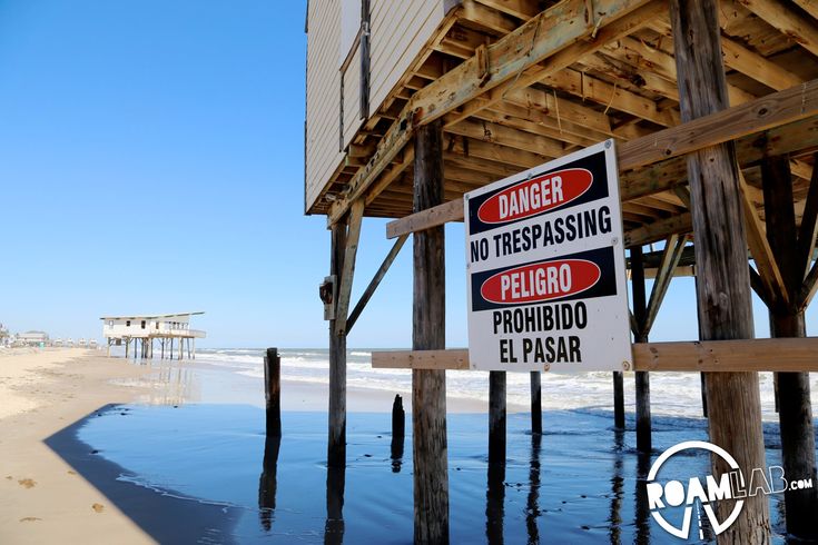 a sign warning people not to trespassing on the beach next to a pier