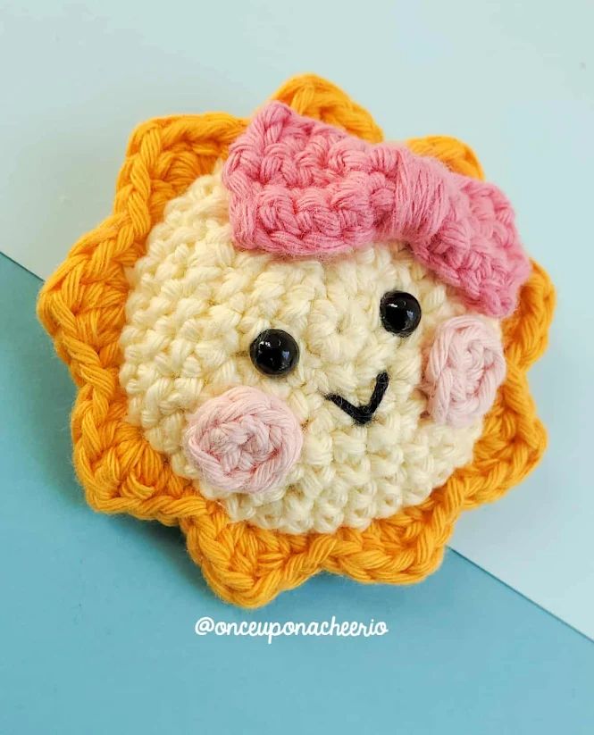 a crocheted brooch with a pink bow on it's head and eyes