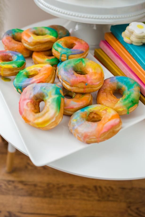 there are many different colored donuts on the plate and some books next to them