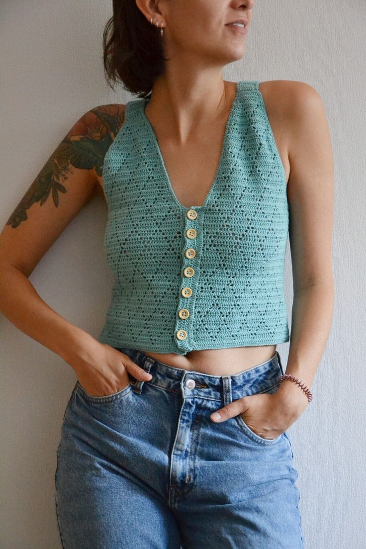 a woman with her hands on her hips wearing jeans and a cropped tank top