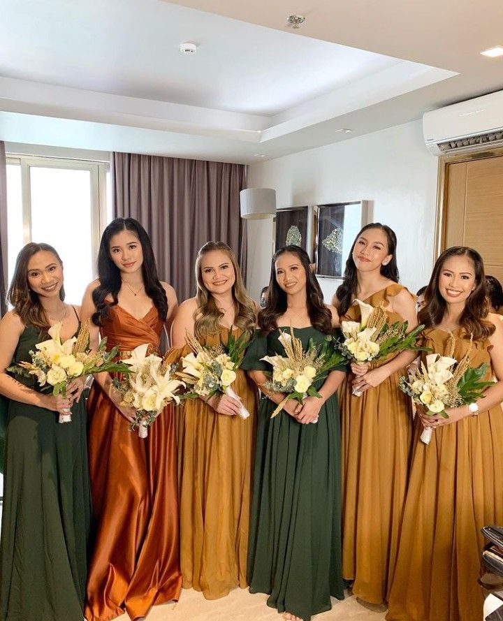 a group of women standing next to each other in long dresses holding bouquets and flowers