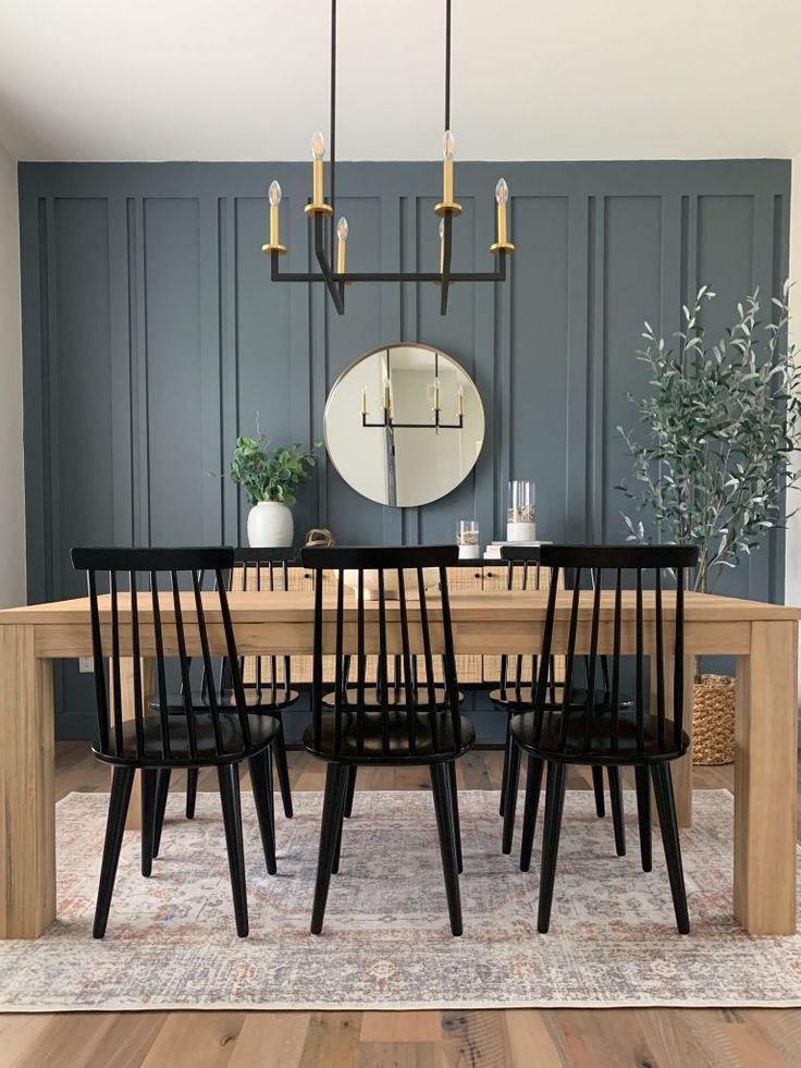 a dining room table with six chairs and a round mirror on the wall above it