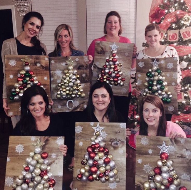 a group of women standing next to each other in front of christmas decorations on wooden boards