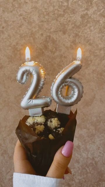 a person holding up a piece of cake with candles in the shape of numbers on it