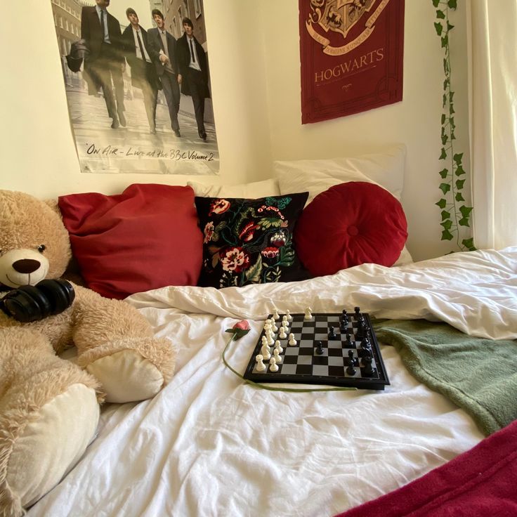 a teddy bear sitting on top of a bed next to a checkerboard board