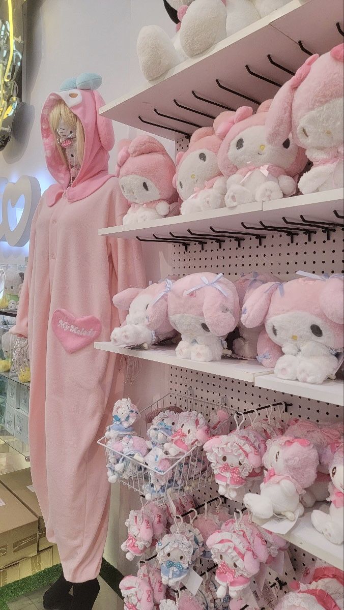 a person in a pink animal onesuit standing next to shelves with stuffed animals on them