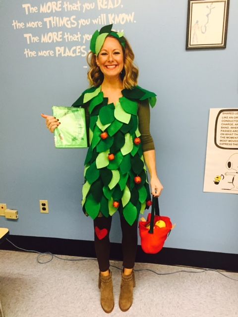 a woman dressed as a christmas tree holding a red bag and wearing a green dress