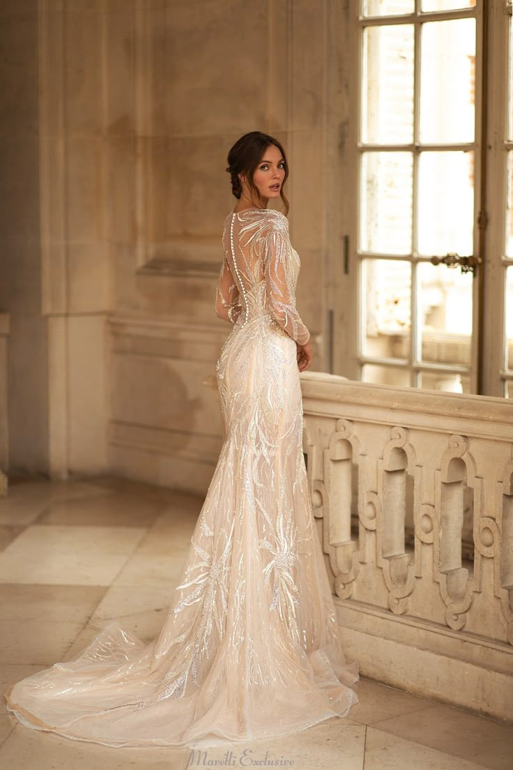 a woman in a wedding dress standing on a balcony looking off into the distance with her back to the camera