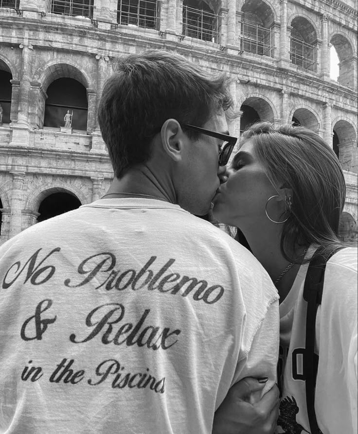 a man and woman kissing each other in front of the colossion, rome