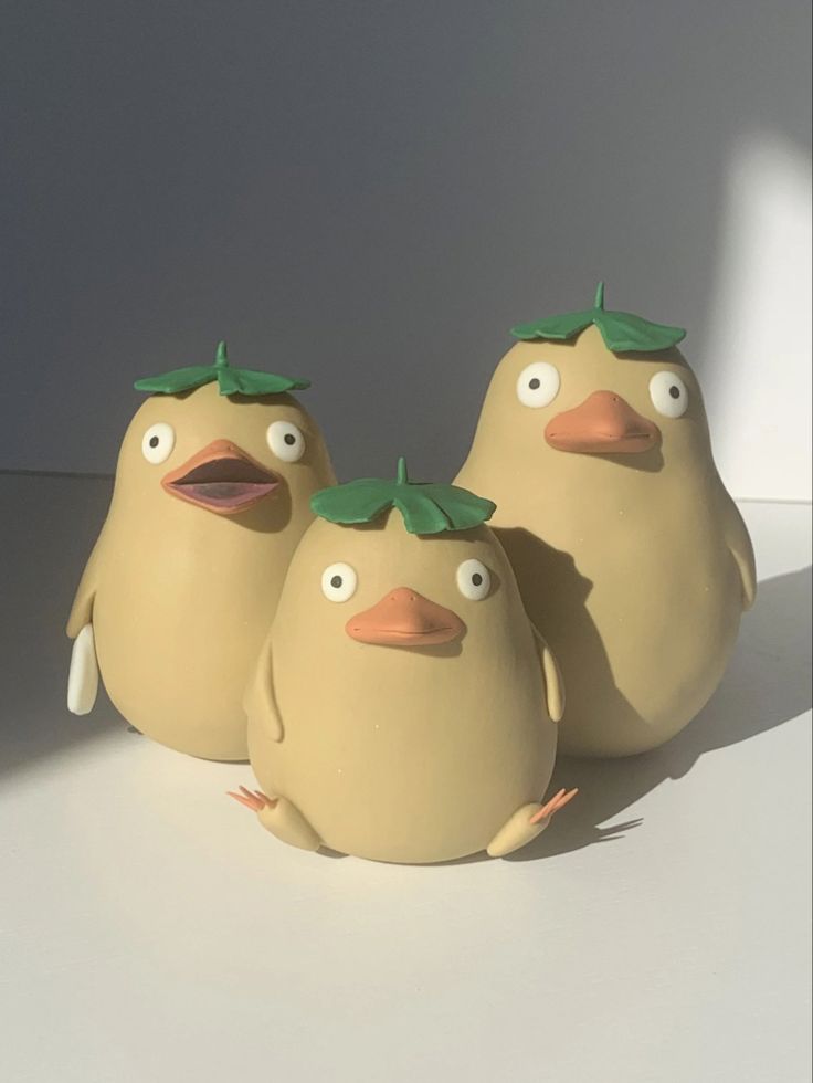 three ceramic birds with green leaves on their heads