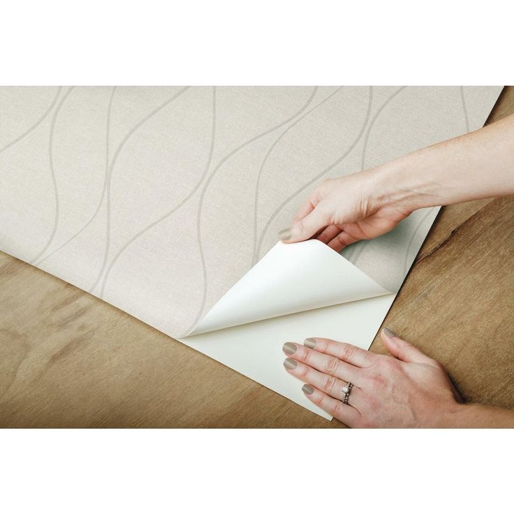 a woman is making a piece of paper on top of a wooden table with her hands