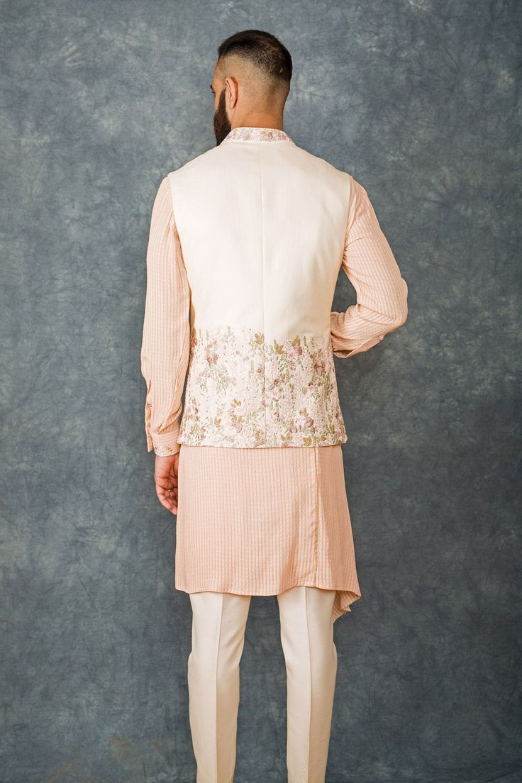 Peach bundi with floral embroidered motifs. Paired with draped kurta and pant.
Components: 3
Fabric: Cotton Silk, Matka Silk, Crepe
Neckline: Mandarin
Sleeve Length: Full
Color: White, Peach
Embroidered
Draped kurta
Front button placket
Floral motif work
Welt pockets
Note: Pocket sqaure worn by the model is not for sale - Aza Fashions Kurta Set For Men, Embroidered Motifs, Nehru Jackets, Fashion App, Kurta Set, Silk Crepe, Embroidered Silk, Cotton Silk, Aza Fashion