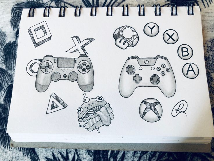 a notebook with some drawings on it and two video game controllers next to each other