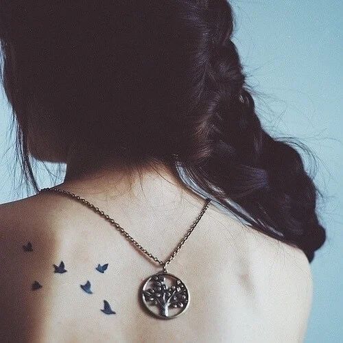 a woman with a tree and birds tattoo on her back