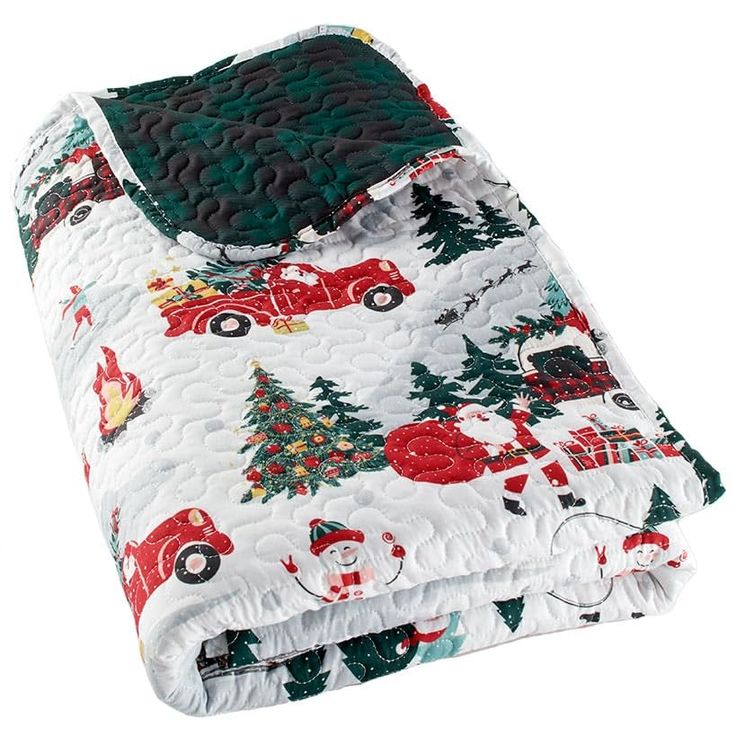 a white quilted blanket with red and green cars, trees, and snowflakes on it