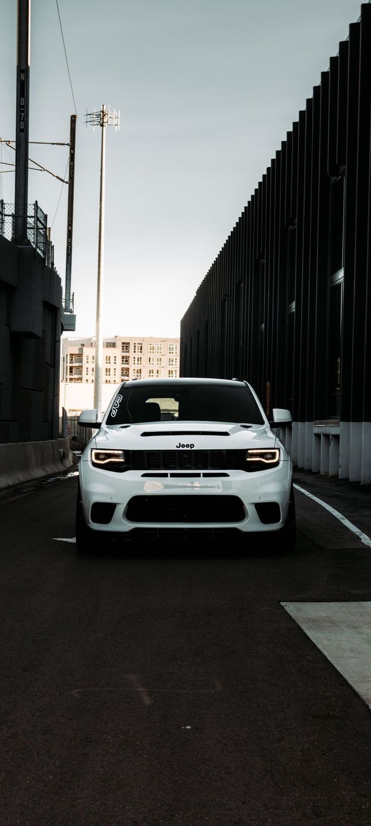 a white car parked in front of a tall building