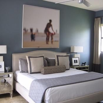 a bedroom with blue walls and white bedding has a large painting on the wall