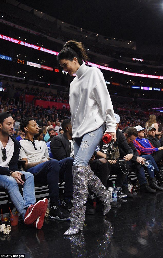 a woman is walking down the runway at a basketball game wearing boots and leggings