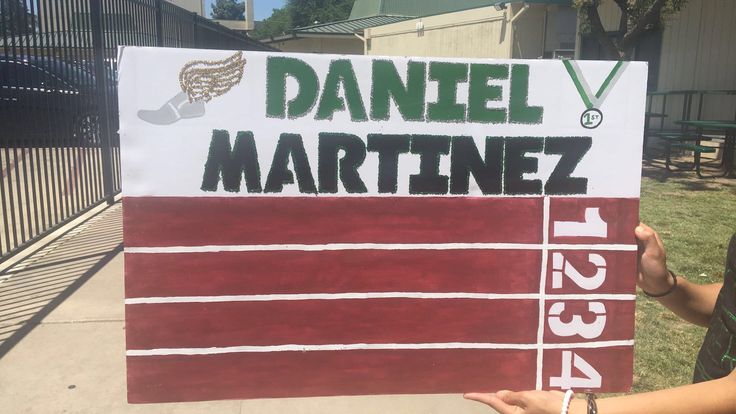 a person holding up a sign that says daniel martine on it in front of a fence