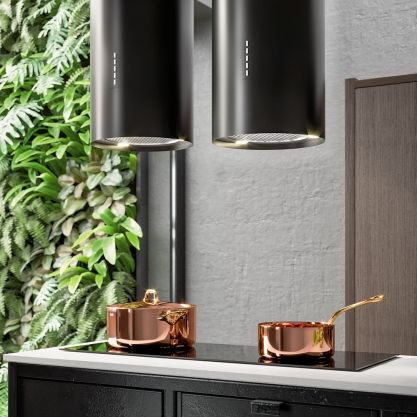 two black lamps hanging from the side of a wall next to a table with copper pots on it