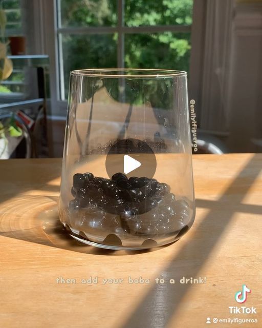 a glass filled with rocks sitting on top of a wooden table