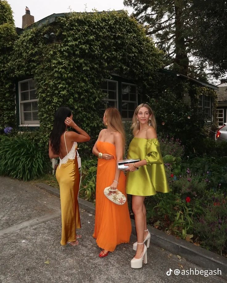 three beautiful women standing next to each other in front of a house with ivy covered walls