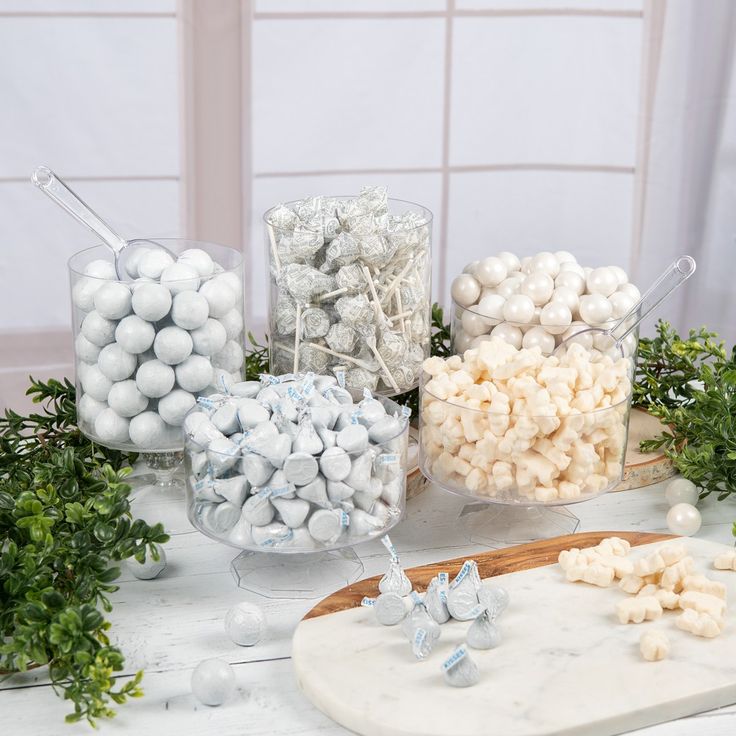 some white and silver candies are on a table next to other candy items, including marshmallows