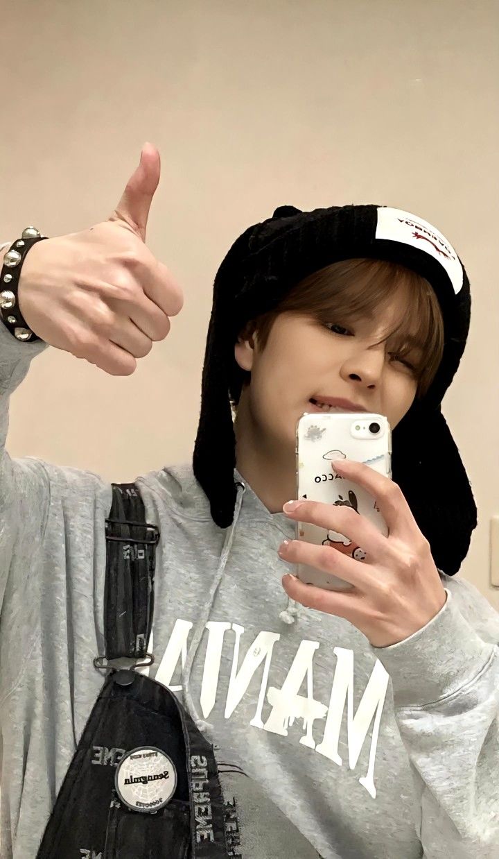 a person taking a selfie in front of a mirror wearing a hat and holding a cell phone