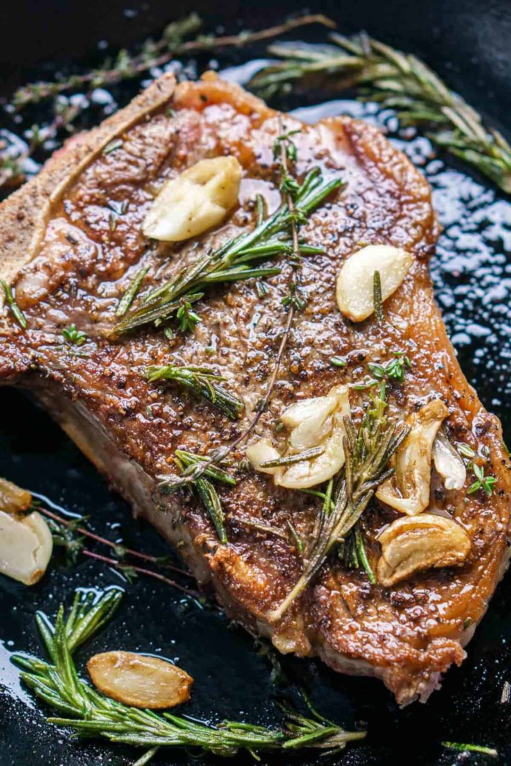 a piece of steak with mushrooms and herbs on a black plate