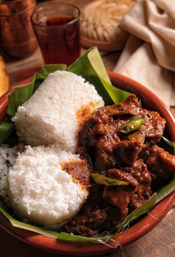 a bowl filled with rice and meat on top of a wooden table